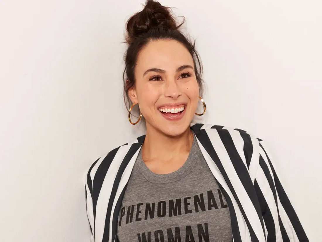 Meena Harris wearing a striped jacket and "Phenomenal Woman" Grey Shirt