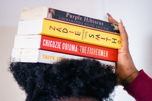Girl with book covering her face with a stack of books